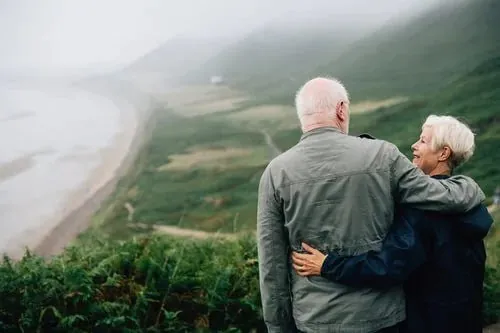 An older couple standing together looking out over a coastal walking track
